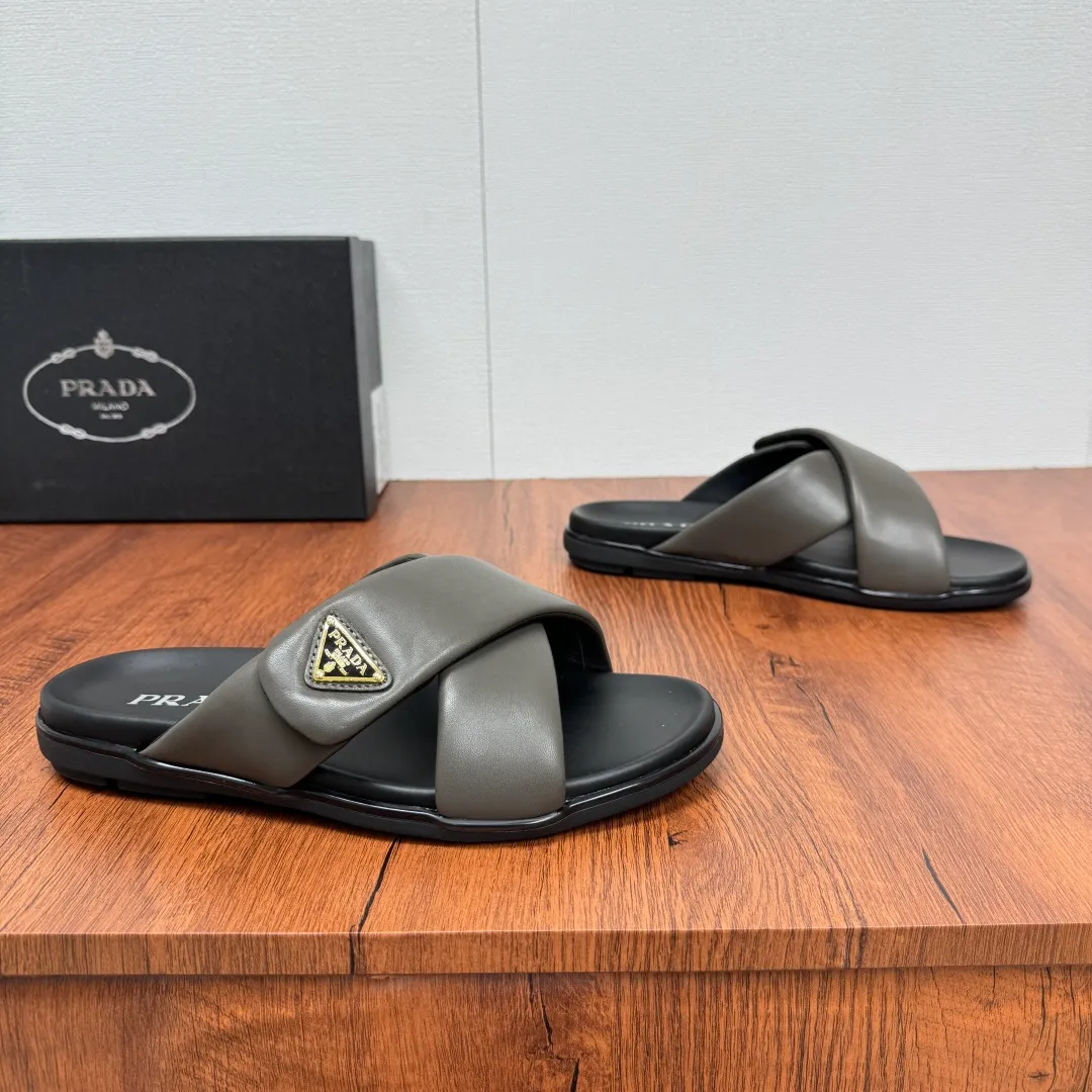 Batch 580 Prada/Prada's new men's leather cross slippers. Velcro closure can finely adjust the size. Calf leather light luxury slippers. Thick soft calf leather wraps the upper. Fat but soft rubber lazy style, soft and comfortable, excellent foot feel. Genuine leather bottom layer, cross style, with a Velcro closure buckle, easy to adjust the appropriate size, and a perfect fit for the wearing experience. The enamel gold triangle logo highlights the brand's classic features. Lightweight rubber thin sole, high foot comfort! Complete package! Size: 39-40-41-42-43-44-45 Leather shoe size Item number: 2X7132 Gray